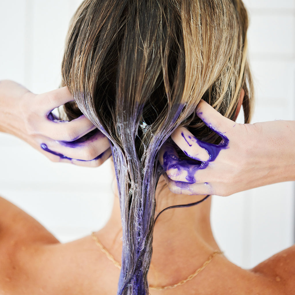Woman toning brassiness out of her blonde hair with BLONDA Toning Purple Shampoo